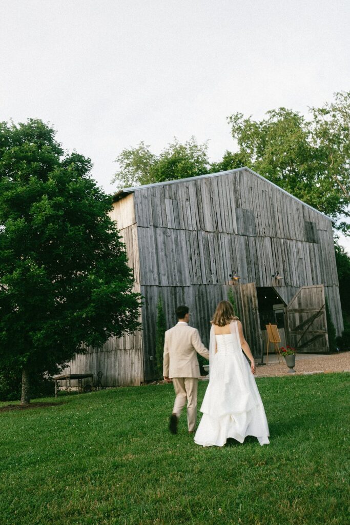 bride and groom walking towards their rustic wedding reception venue in nashville, southall meadows