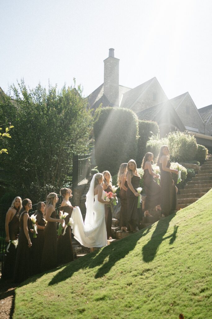 photograph of a bride and her bridal party walking up a steep grass hill at her nashville wedding venue