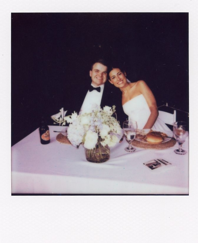 bride and groom smiling at their reception table in a candid Polaroid-style image captured by one of the top Nashville wedding photographers