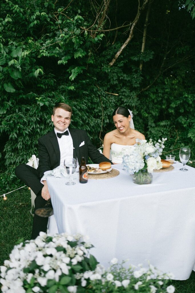 bride and groom seated at their sweetheart table surrounded by greenery, captured by photographers in Nashville Tennessee
