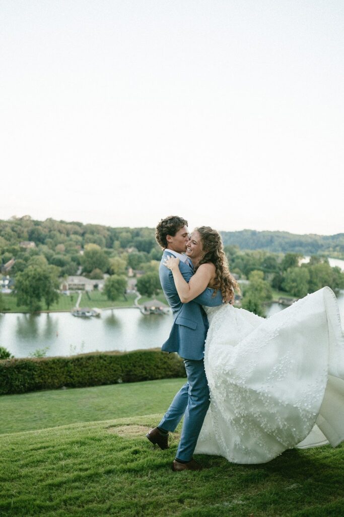 bride and groom laughing together on a scenic lawn overlooking the water, captured by wedding photographers in Nashville TN during golden hour