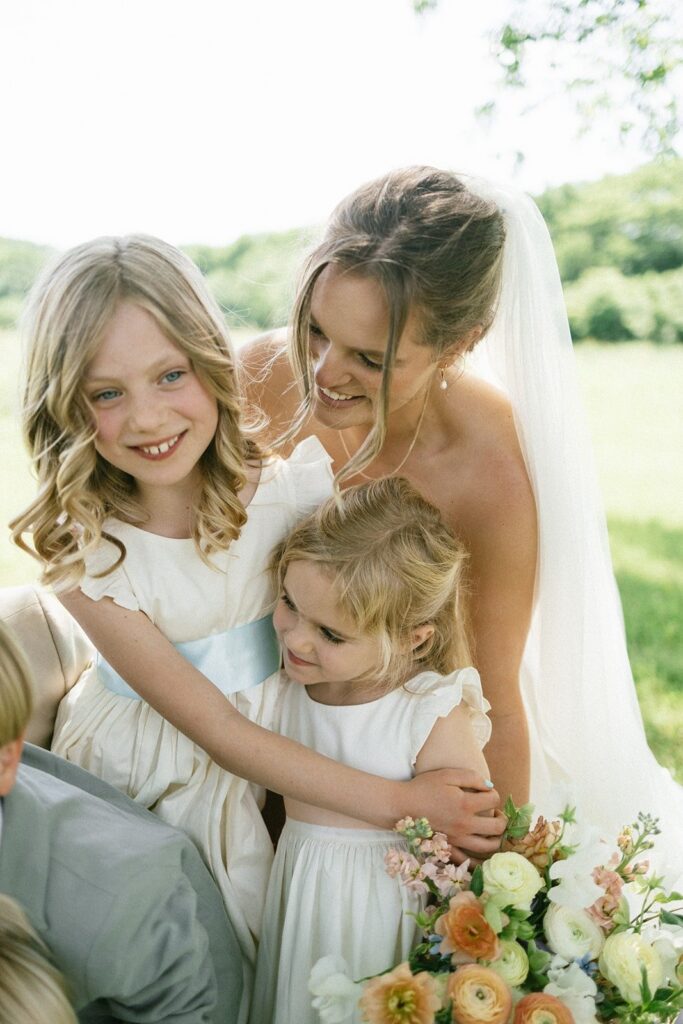 bride hugging two flower girls during an outdoor ceremony photographed by wedding photographers in Nashville TN