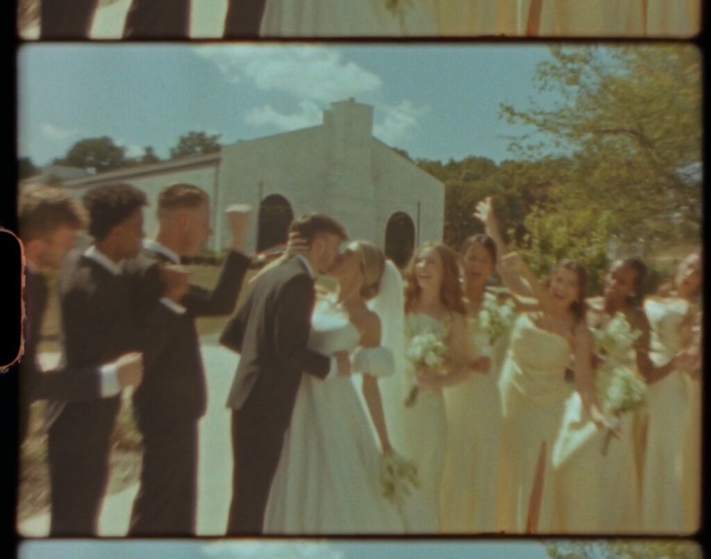 bride and groom sharing a kiss surrounded by their wedding party outside a white chapel in Nashville TN