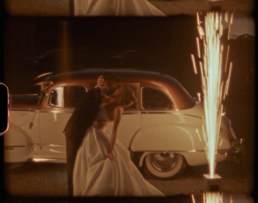 bride and groom sharing a romantic dip kiss beside a vintage car with sparklers at their Nashville TN wedding reception