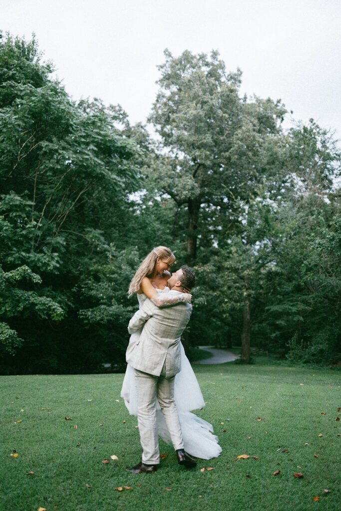 bride and groom embracing on a grassy lawn surrounded by trees, captured by wedding photographers in Nashville TN