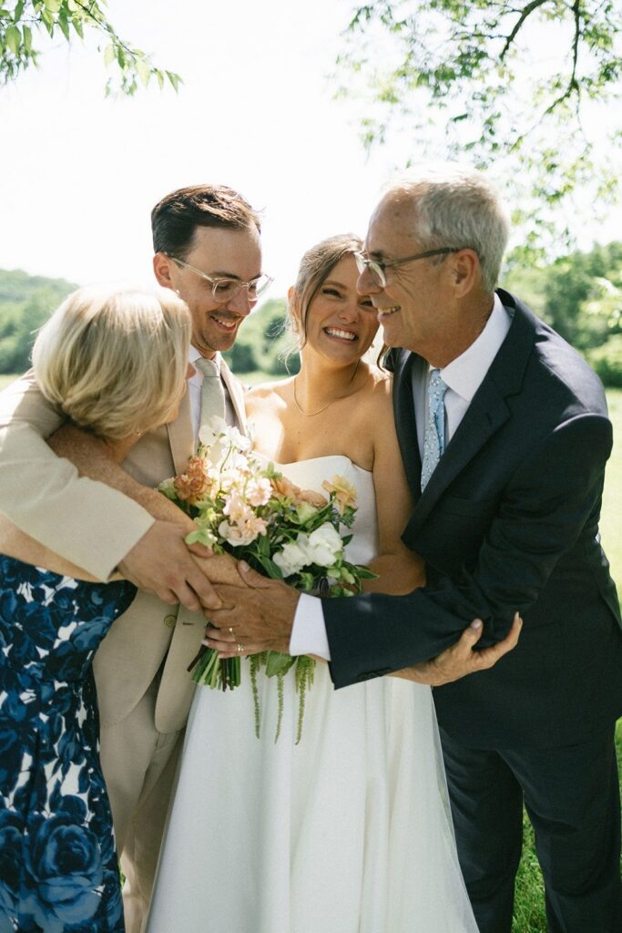 bride and groom embracing parents in a joyful outdoor portrait by photographers in Nashville Tennessee