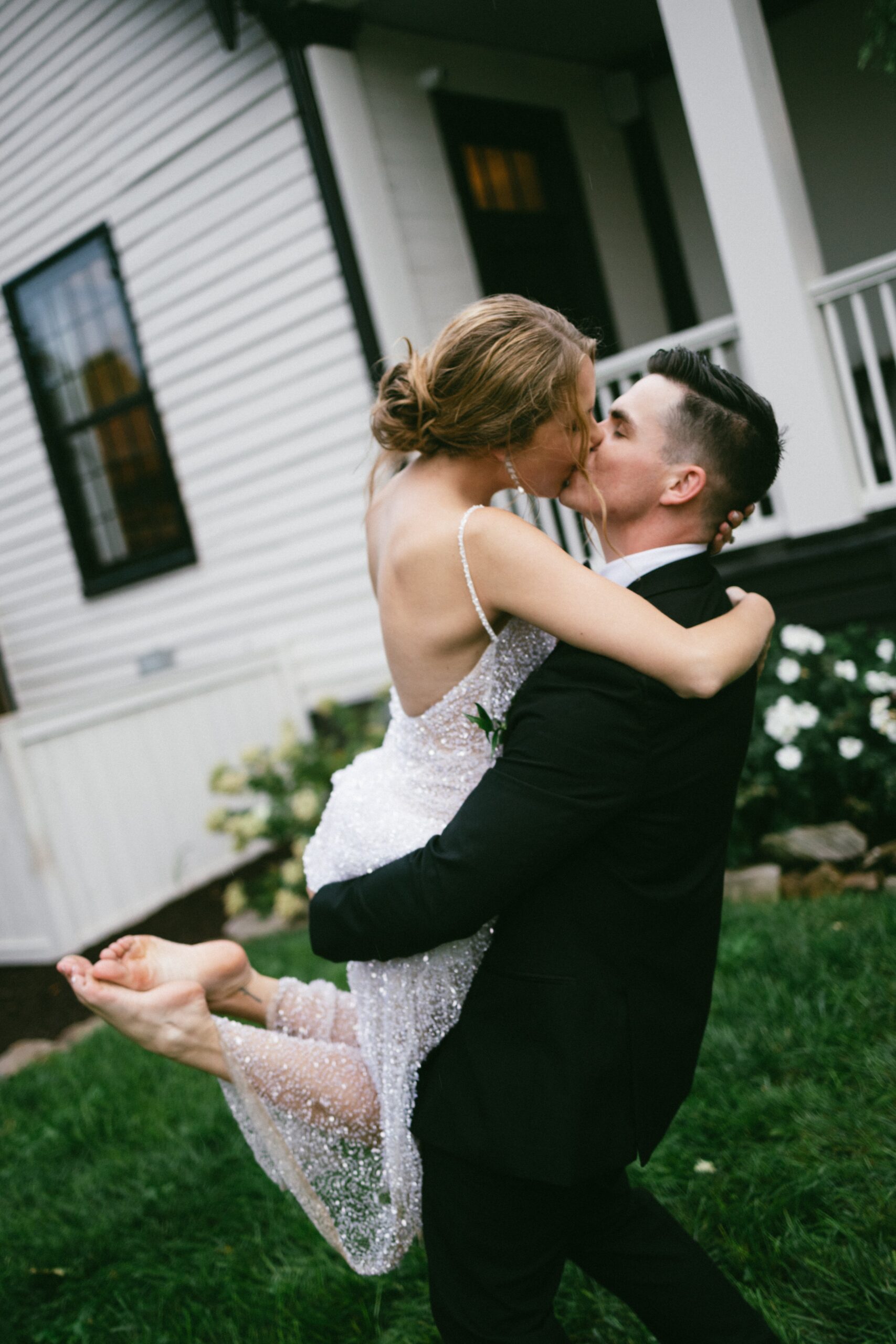 Bride jumping into the groom’s arms for a joyful kiss on the lawn outside a charming historic home at one of the romantic small wedding chapels Nashville TN couples love.