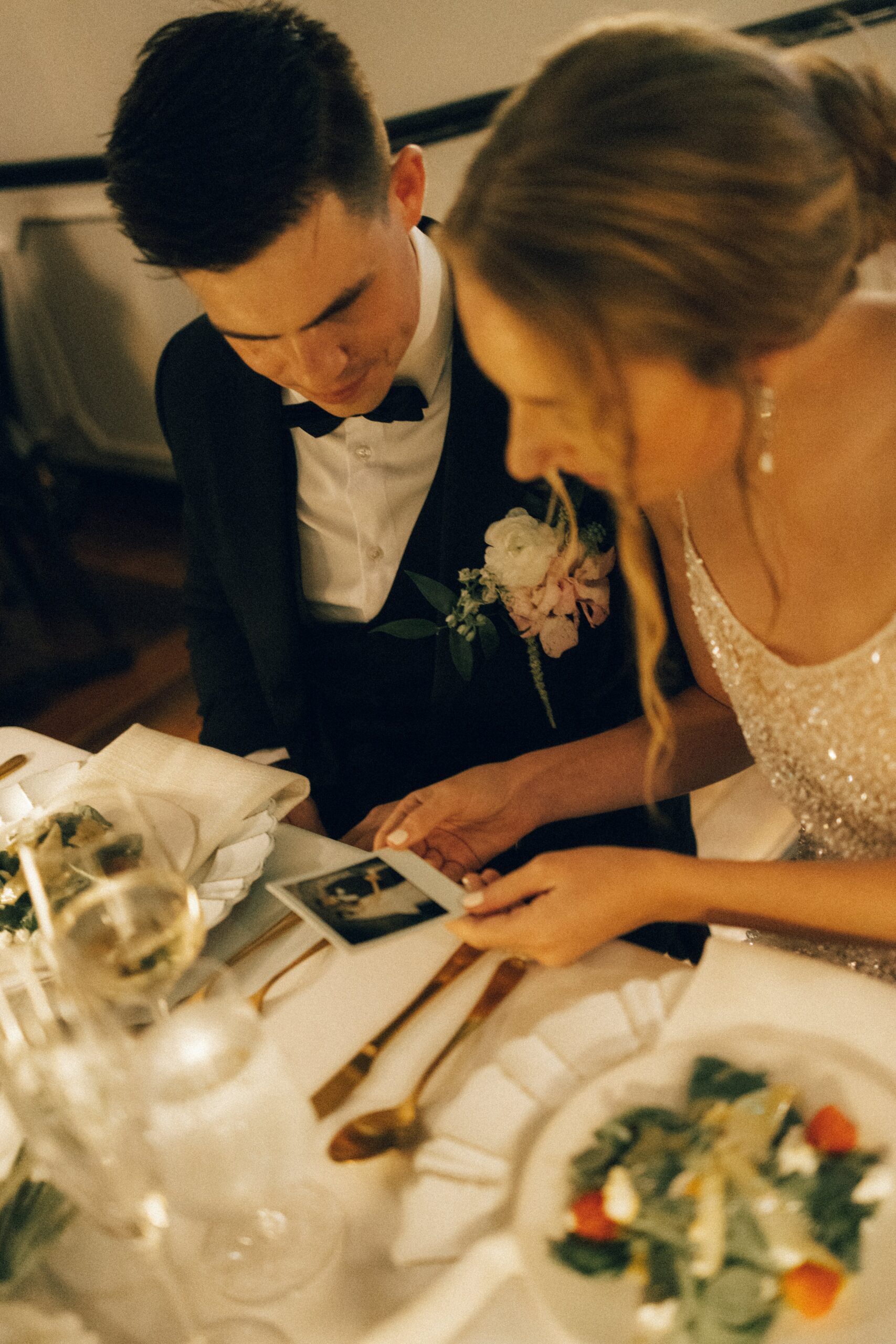 Bride and groom looking through instant photos at their candlelit reception table during an intimate celebration at one of the charming small wedding venues near Nashville TN.