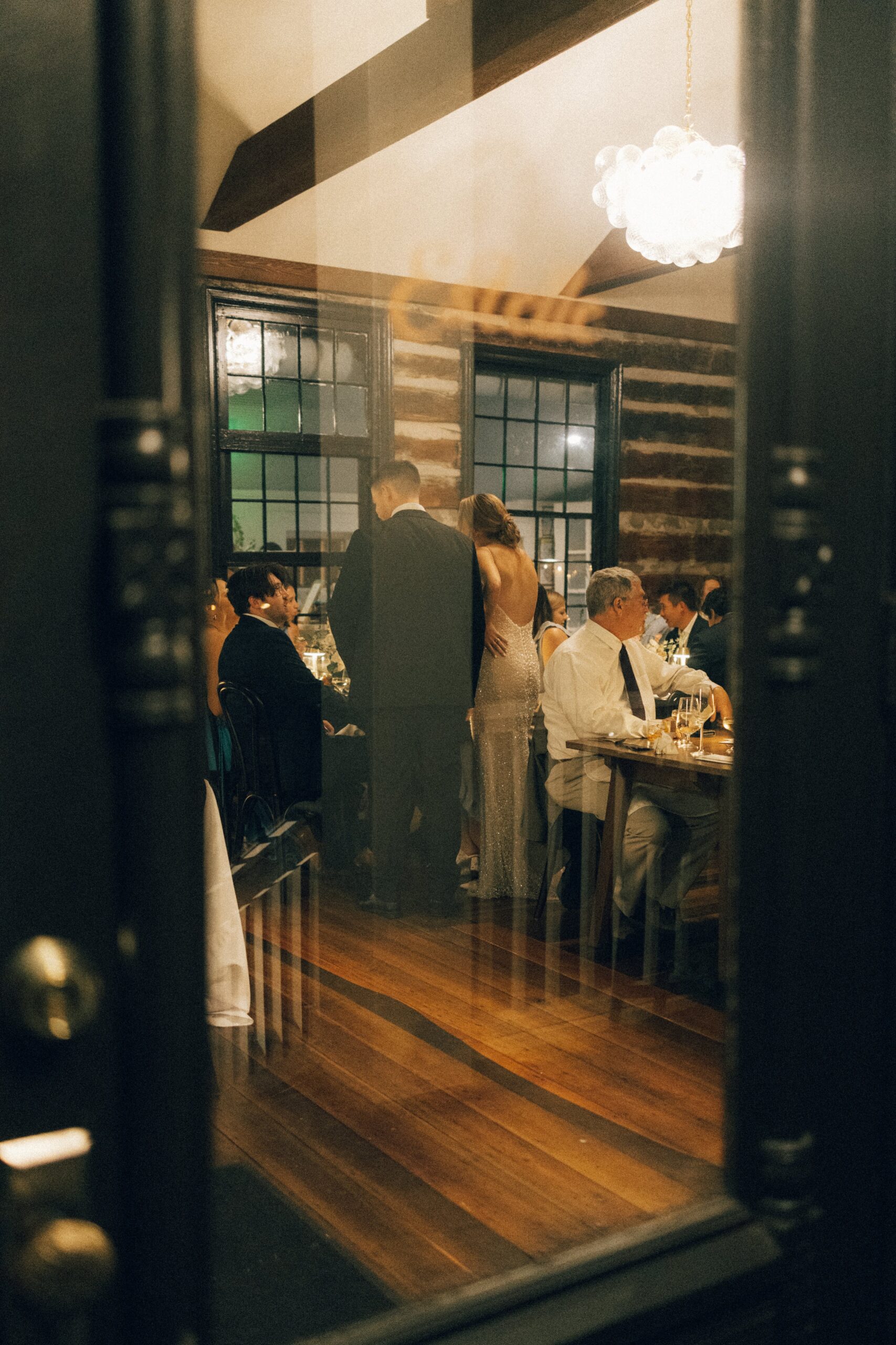 Newlyweds walking between guests during an elegant dinner reception inside a cozy historic space, highlighting intimate wedding venues in Nashville TN.