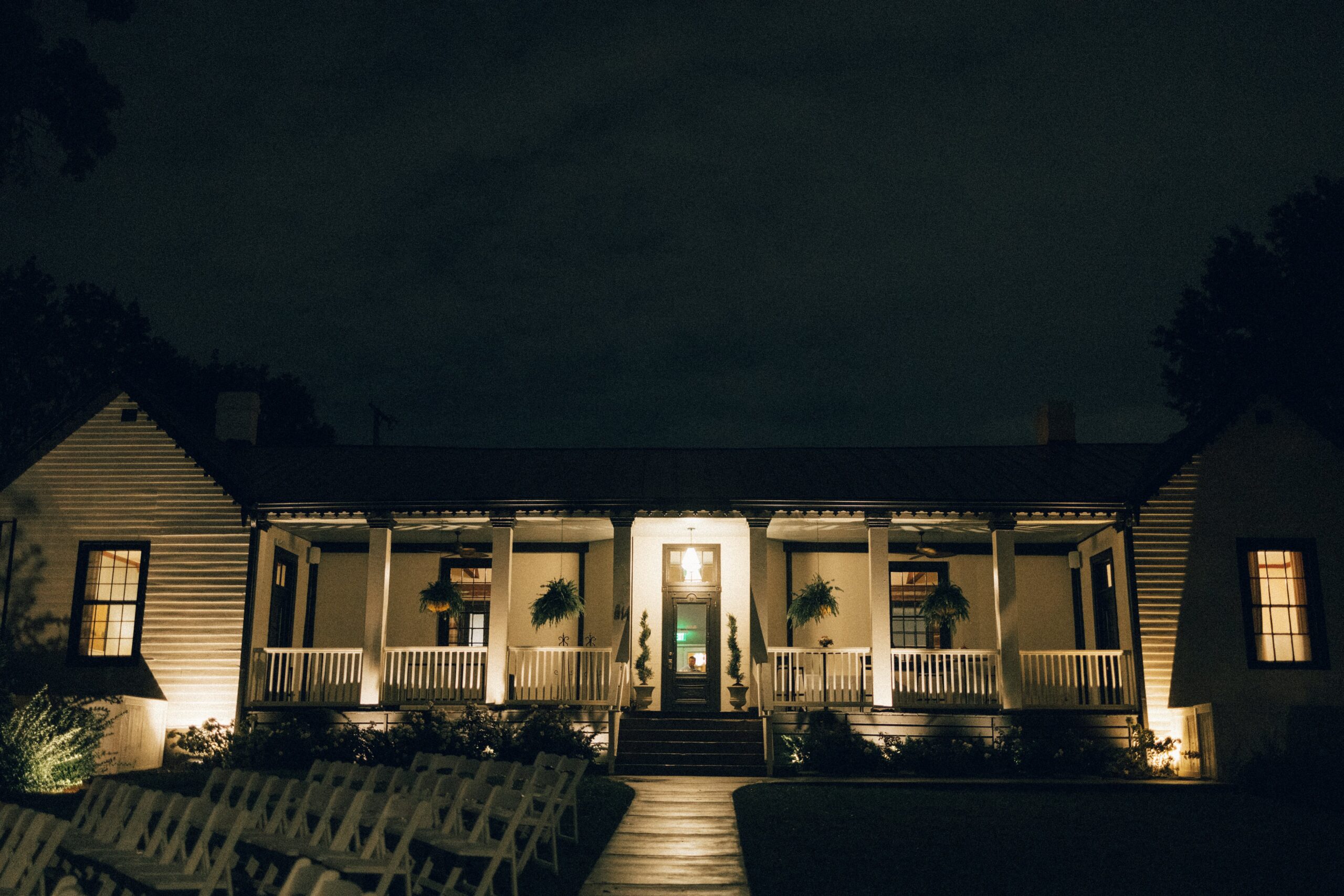 Historic white estate illuminated at night with ceremony chairs set outside, showcasing one of the most romantic small wedding venues in Nashville TN.