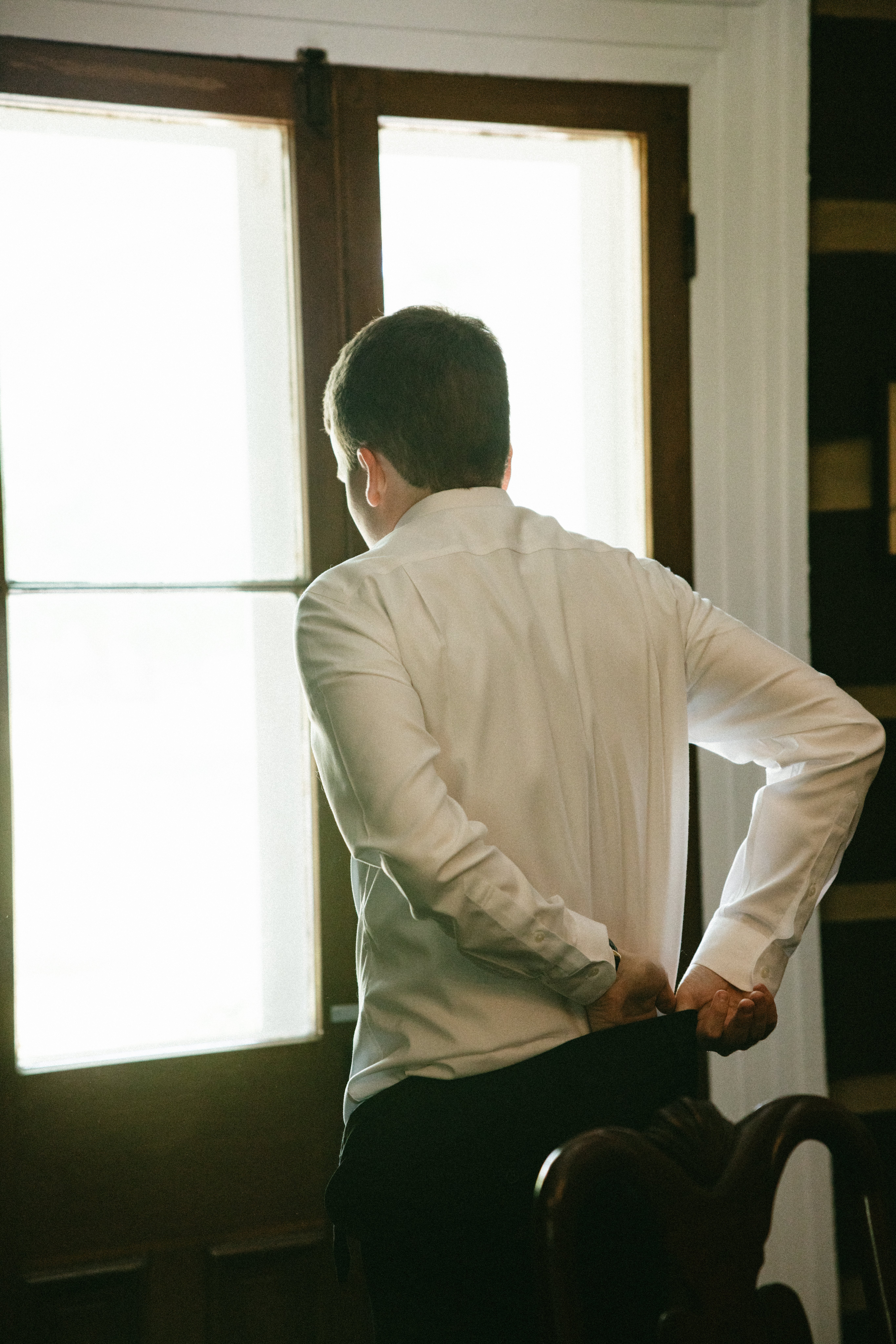 Groom adjusting his shirt cuffs near a window while getting ready inside a historic estate, a common scene at small wedding venues Nashville TN couples choose for intimate celebrations.