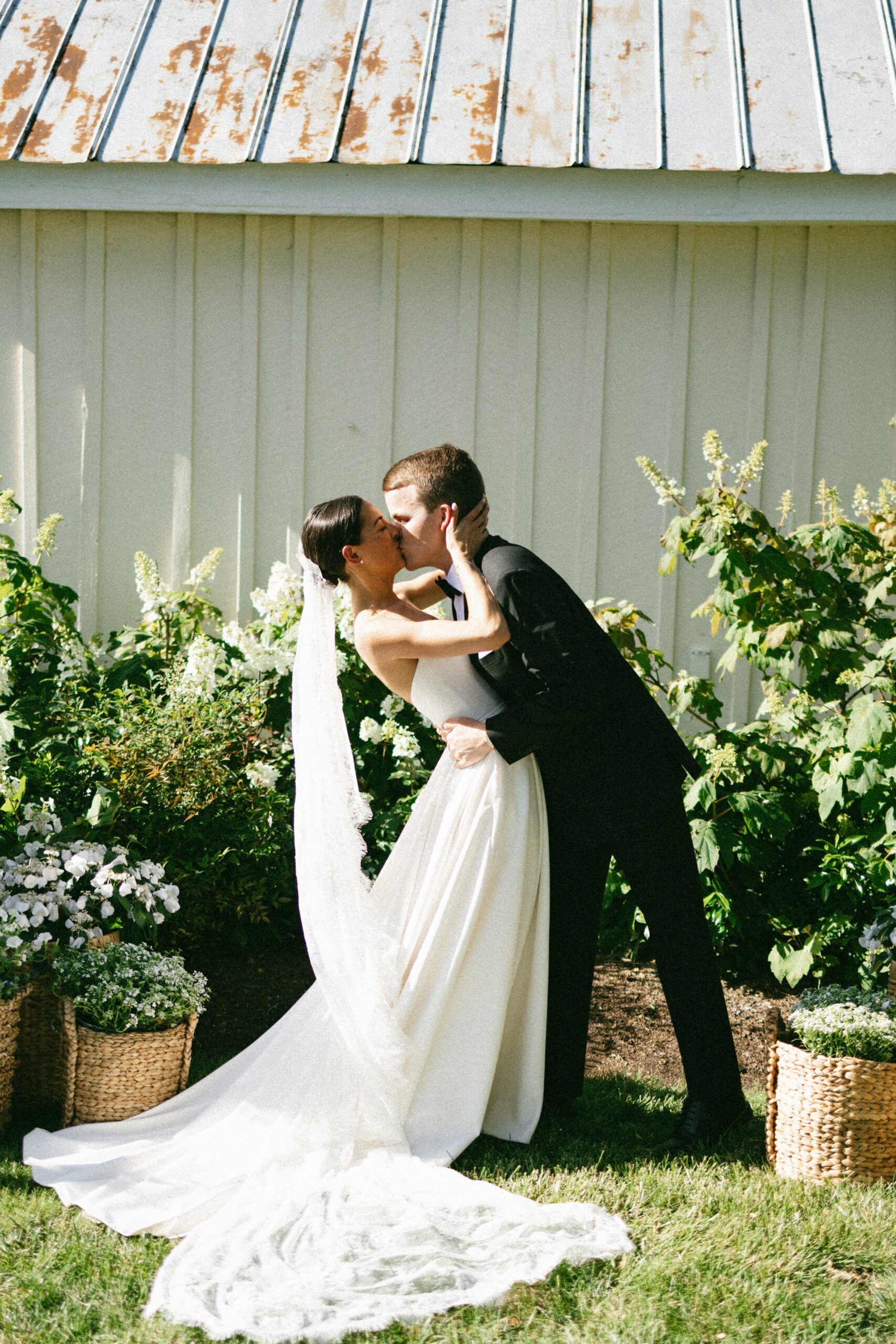Newly married couple sharing their first kiss in front of a rustic white chapel and garden florals at one of the most beautiful intimate wedding venues in Nashville TN.