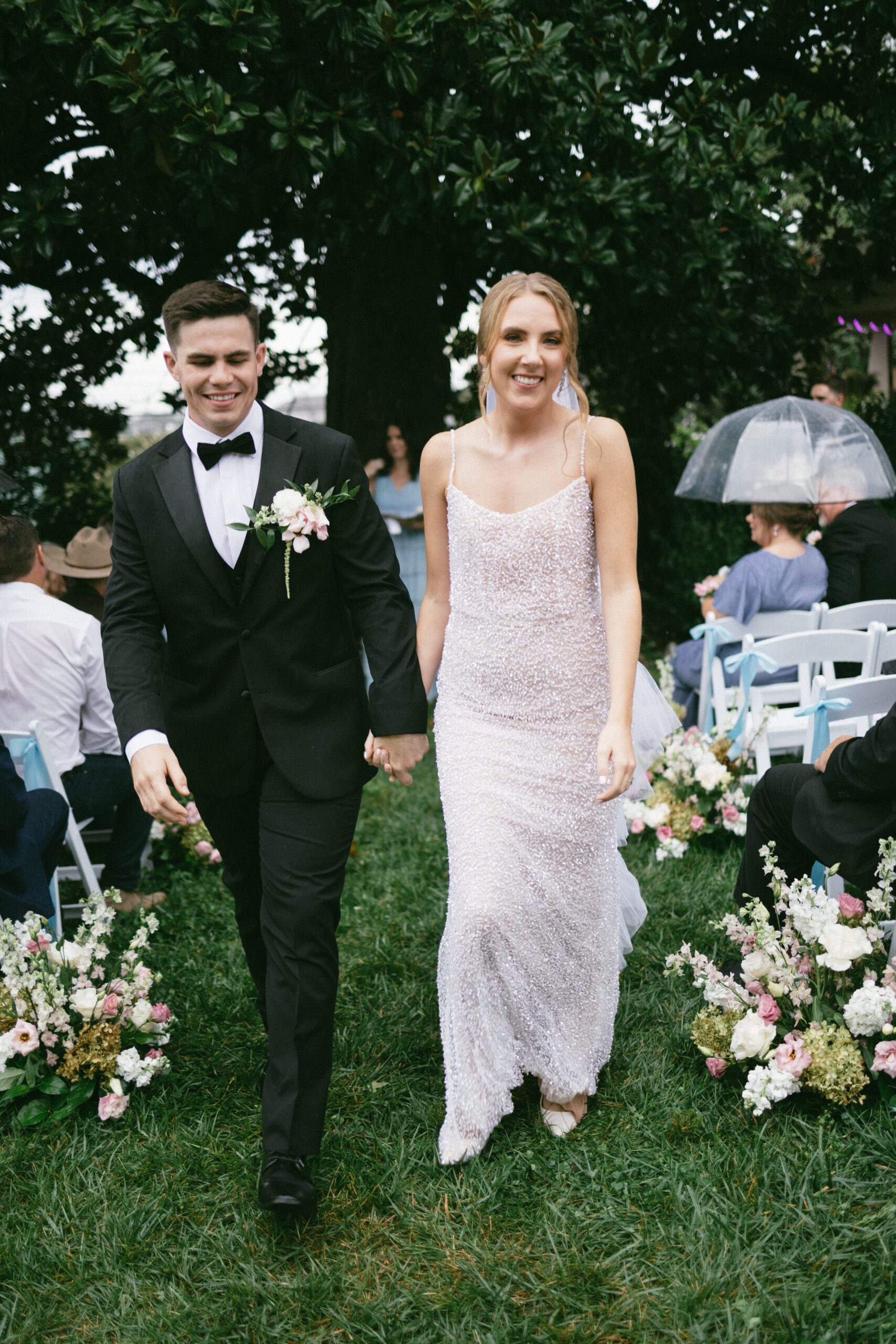 Newly married couple walking down the ceremony aisle together while guests look on during a celebration at one of the charming small wedding venues near Nashville TN.