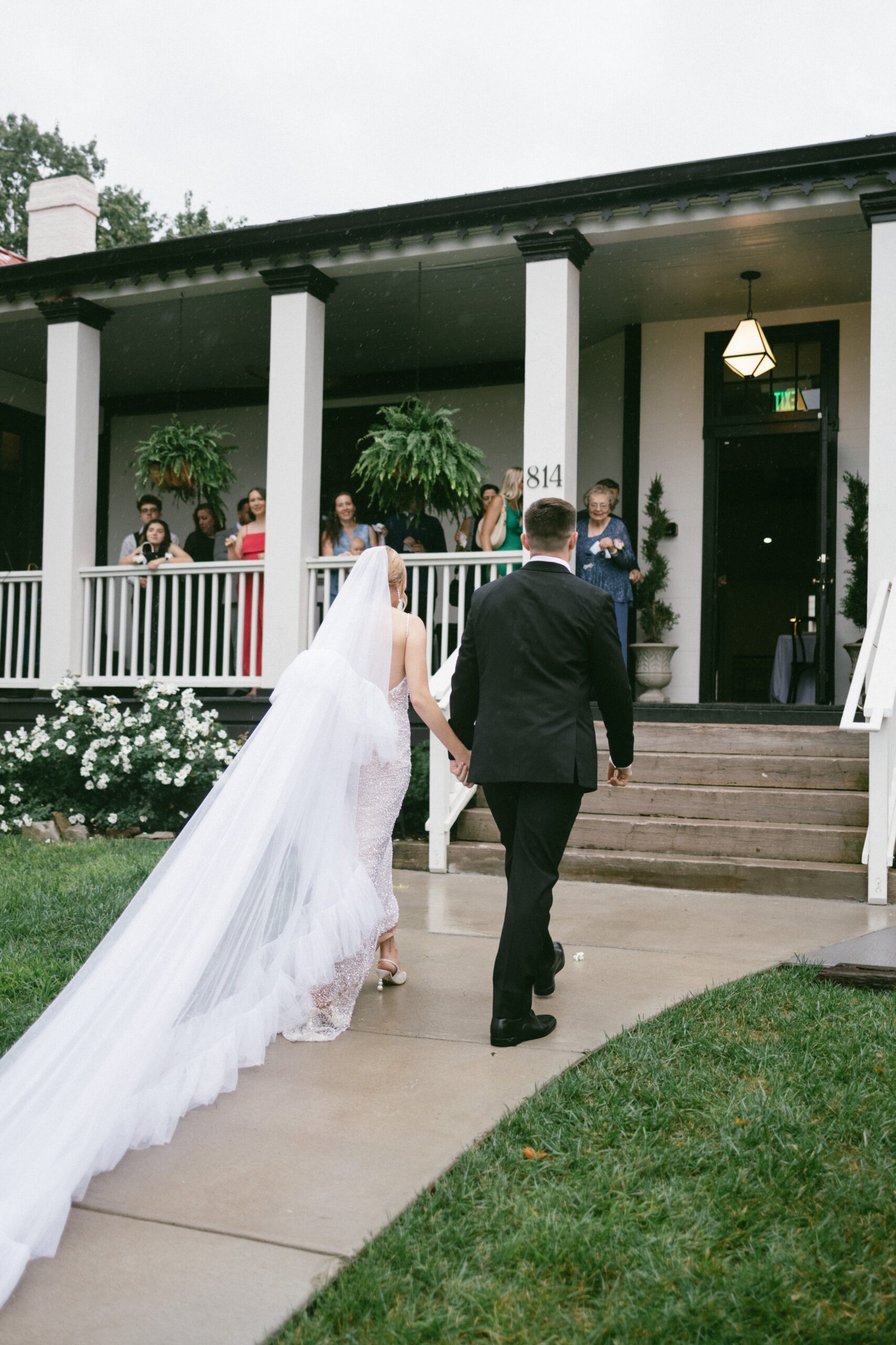 Bride and groom walking hand in hand toward a historic white porch reception space after their ceremony at one of the elegant small wedding venues Nashville TN couples love.