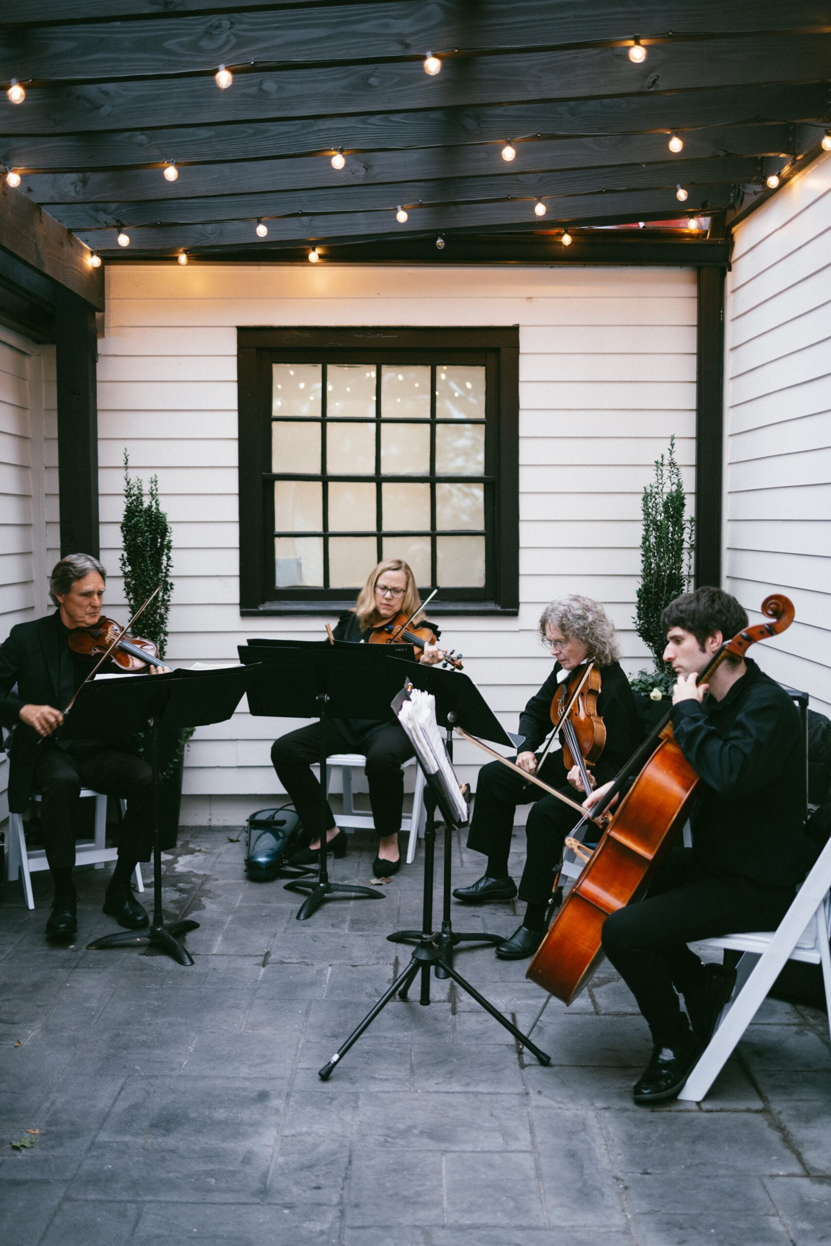 String quartet performing live music on a cozy patio beneath café lights at one of the elegant wedding chapels in Nashville TN for an intimate ceremony.