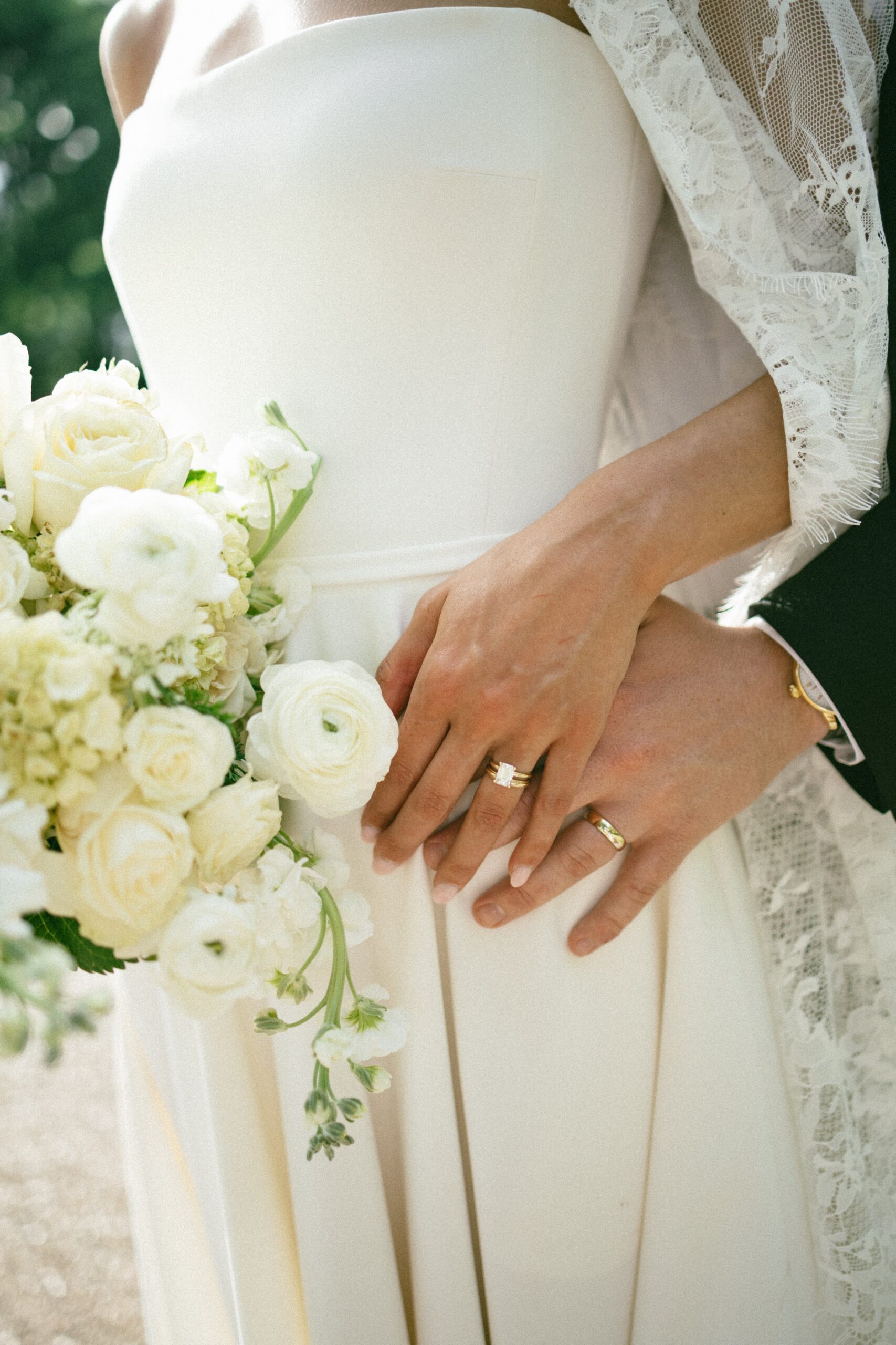 Close-up of bride and groom’s wedding rings as they hold hands beside a bouquet of white roses at one of the romantic small wedding chapels Nashville TN couples love.