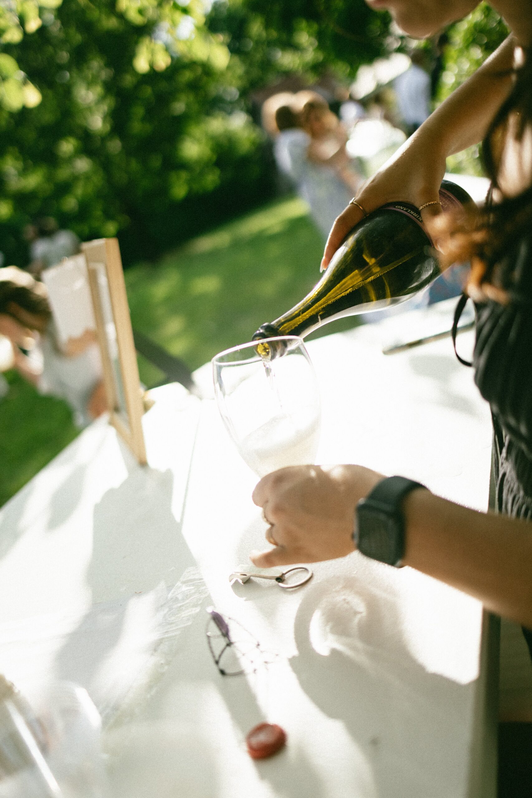 Bartender pouring sparkling wine into a glass at an outdoor reception bar set up at one of the intimate wedding venues in Nashville TN.