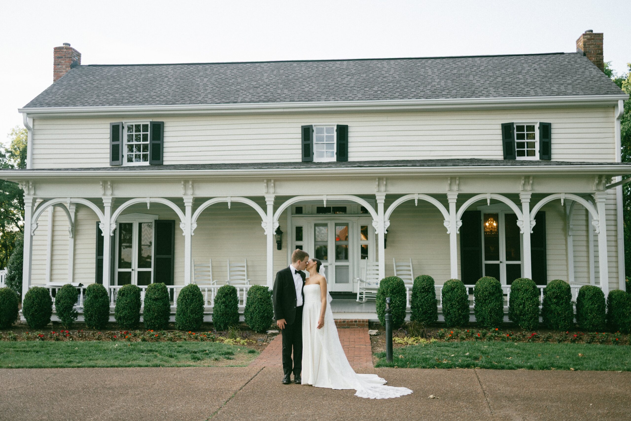 Bride and groom sharing a kiss in front of a charming historic home at one of the most beautiful small wedding venues in Nashville TN.