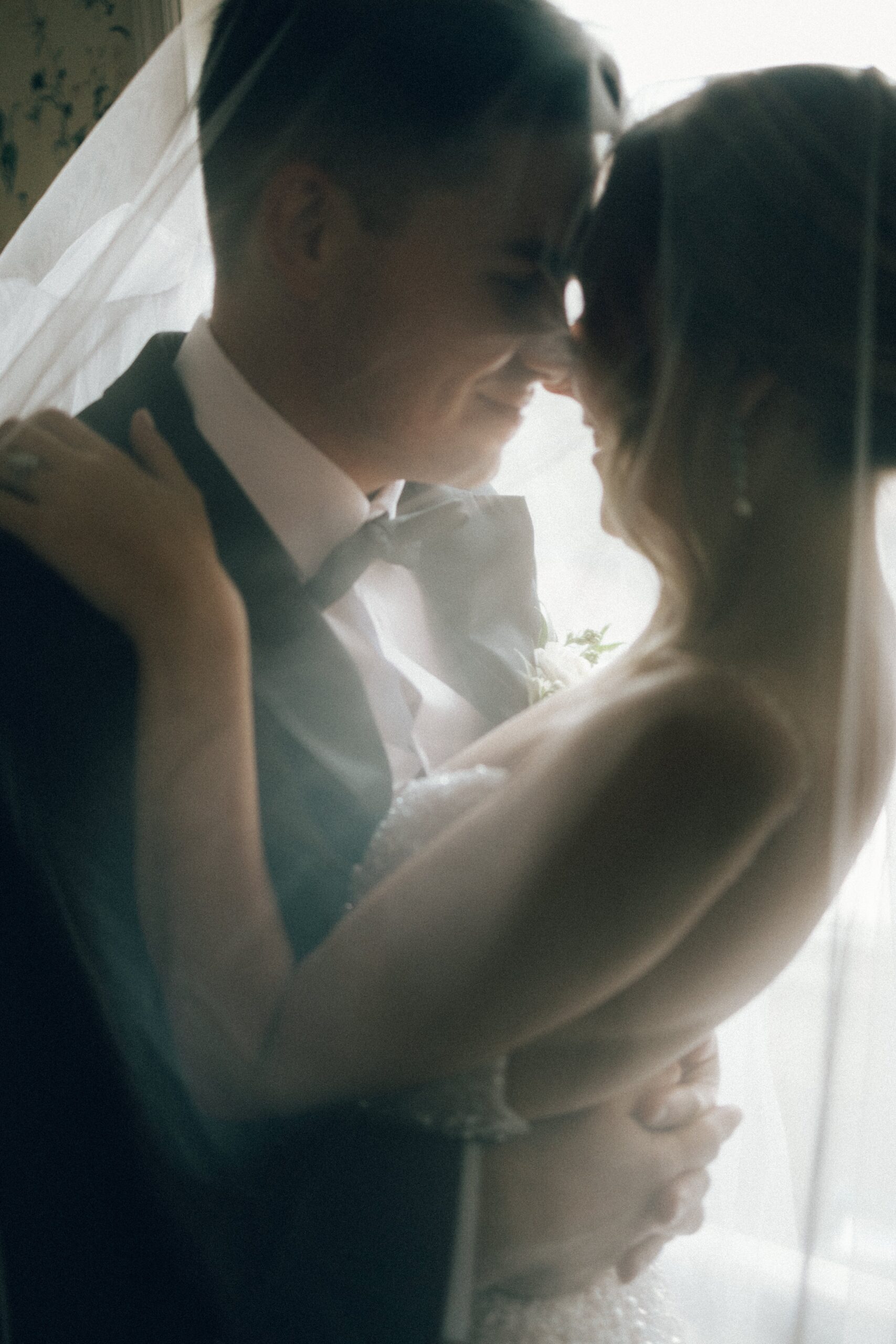 Bride and groom share a soft, romantic moment by a window with natural light during an intimate wedding day at one of the intimate wedding venues in Nashville TN.