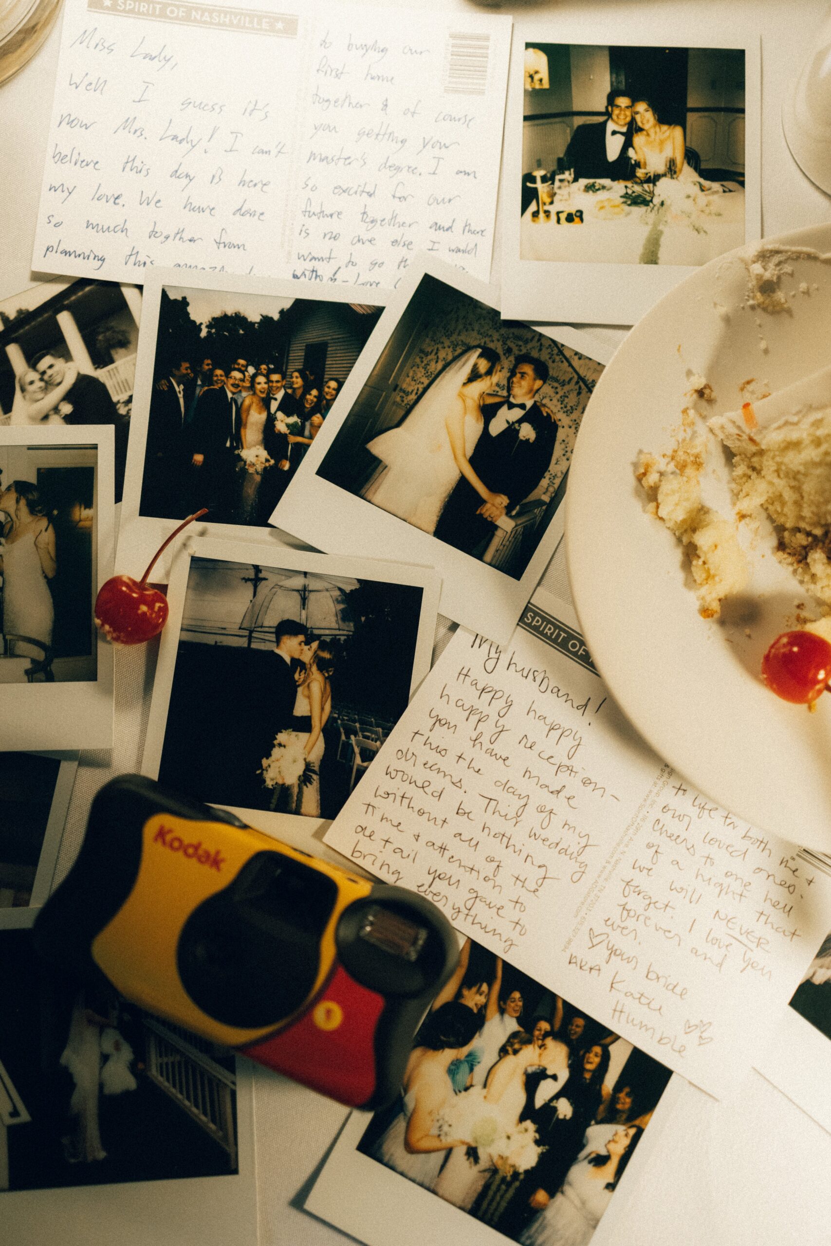 Disposable camera, polaroid photos, and handwritten notes scattered across a reception table at a small wedding venue in Nashville TN.