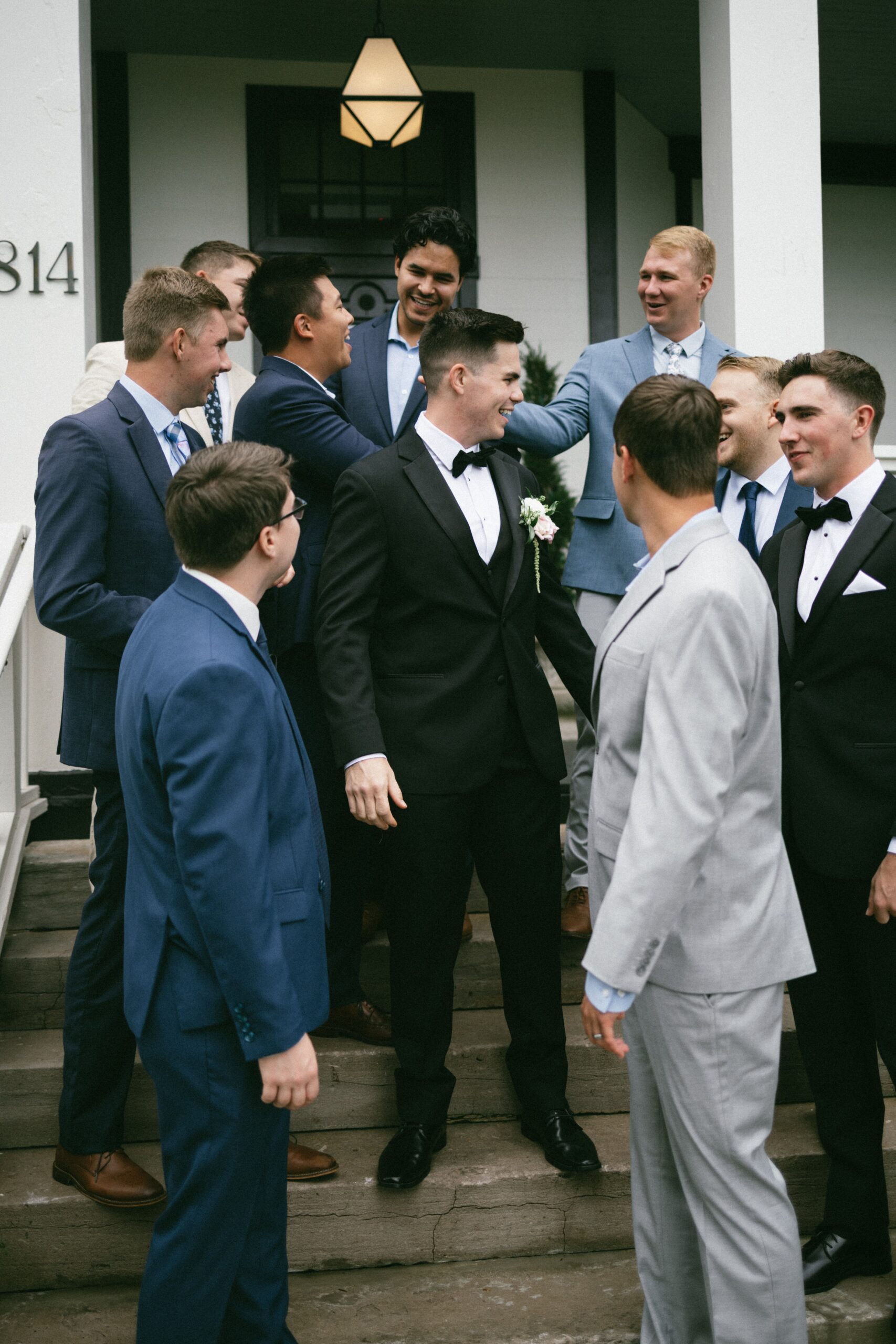 Groom laughing with his groomsmen on the front steps of a charming small wedding venue in Nashville TN.