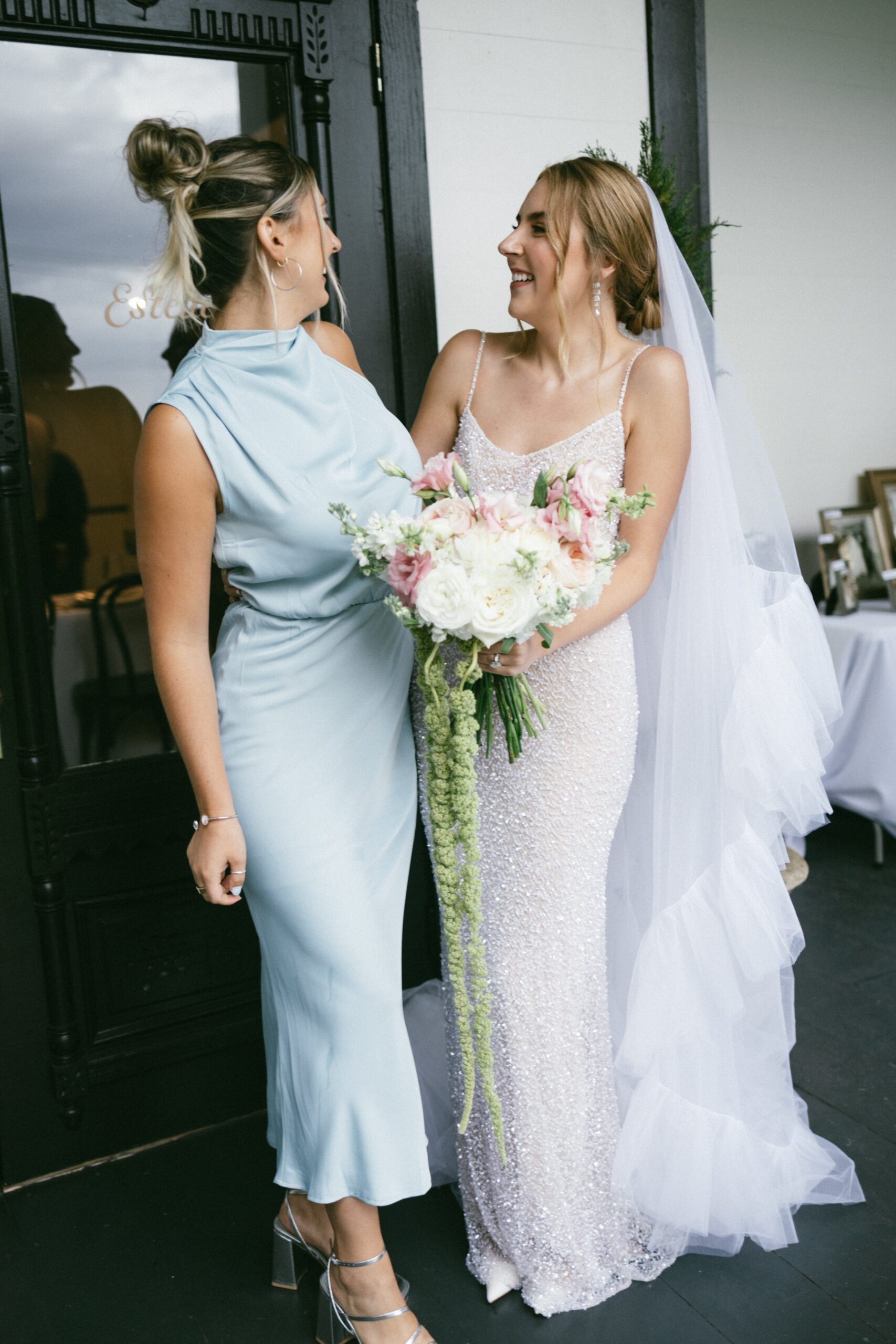 Bride holding her bouquet while laughing with a bridesmaid outside one of the romantic small wedding venues Nashville TN couples love.