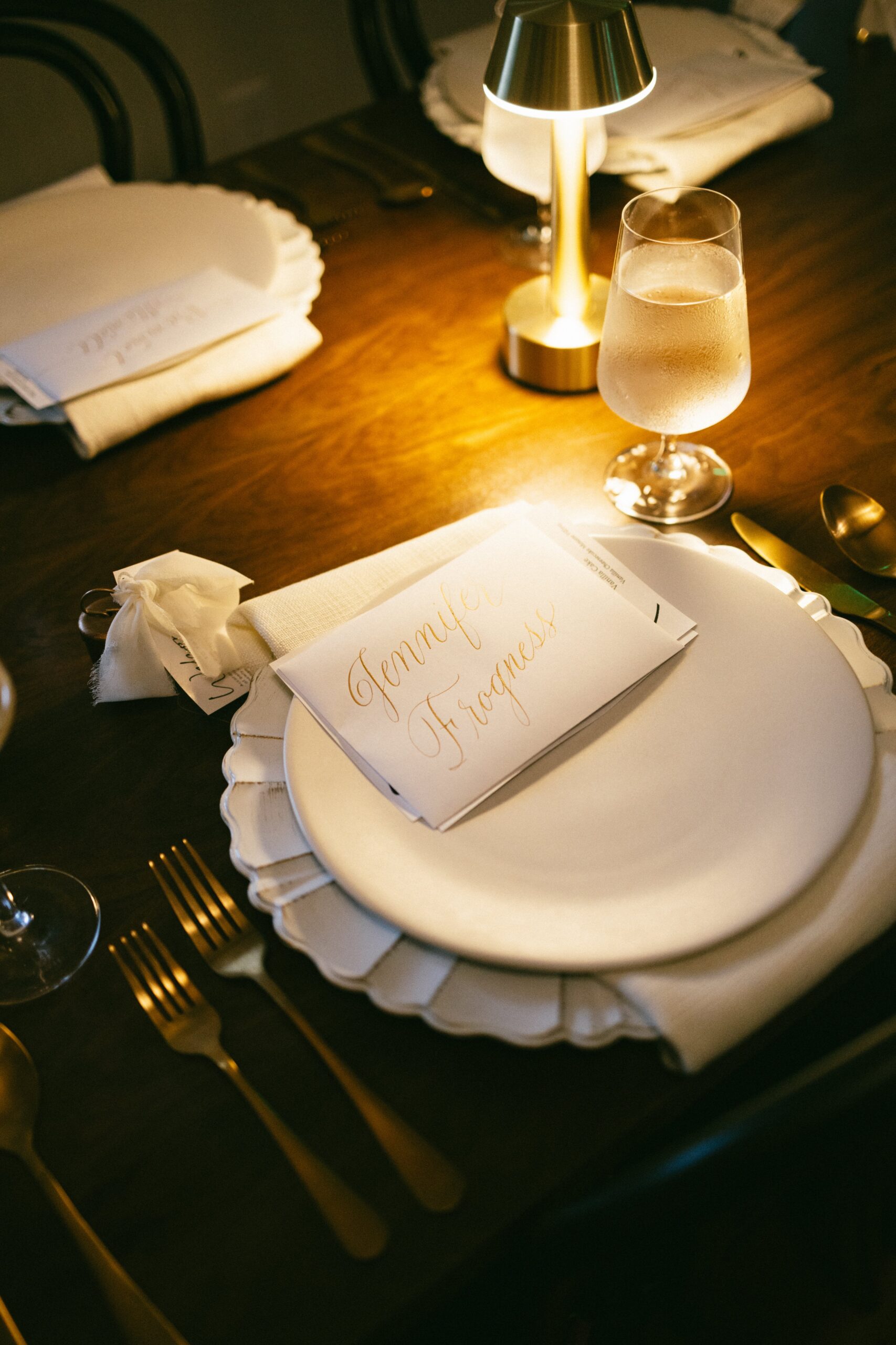 Wedding place setting with handwritten name card, gold flatware, and candlelight at an intimate reception in one of the small wedding chapels in Nashville TN.