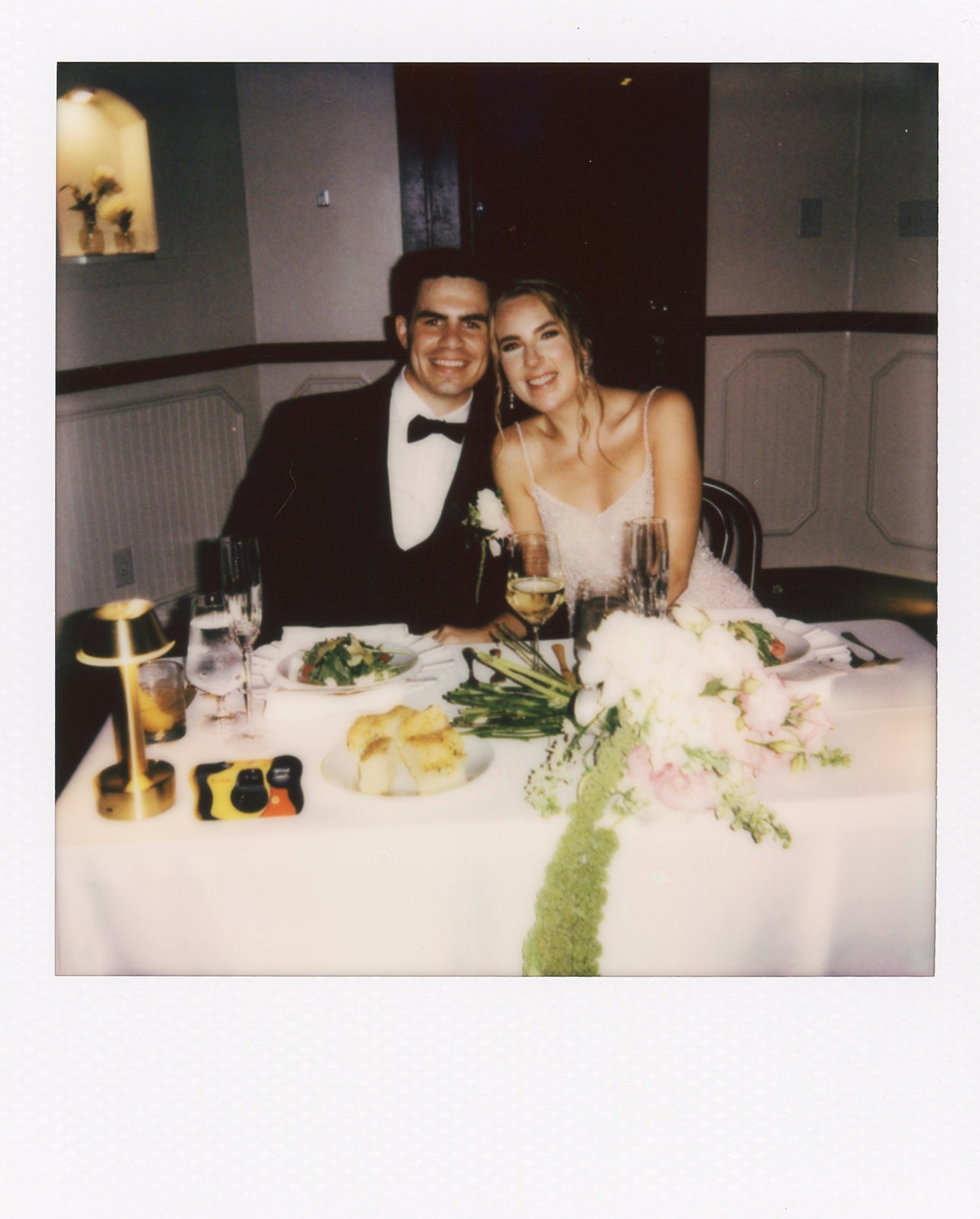 bride and groom sitting at their wedding reception table during their estelle nashville wedding photo in polaroid